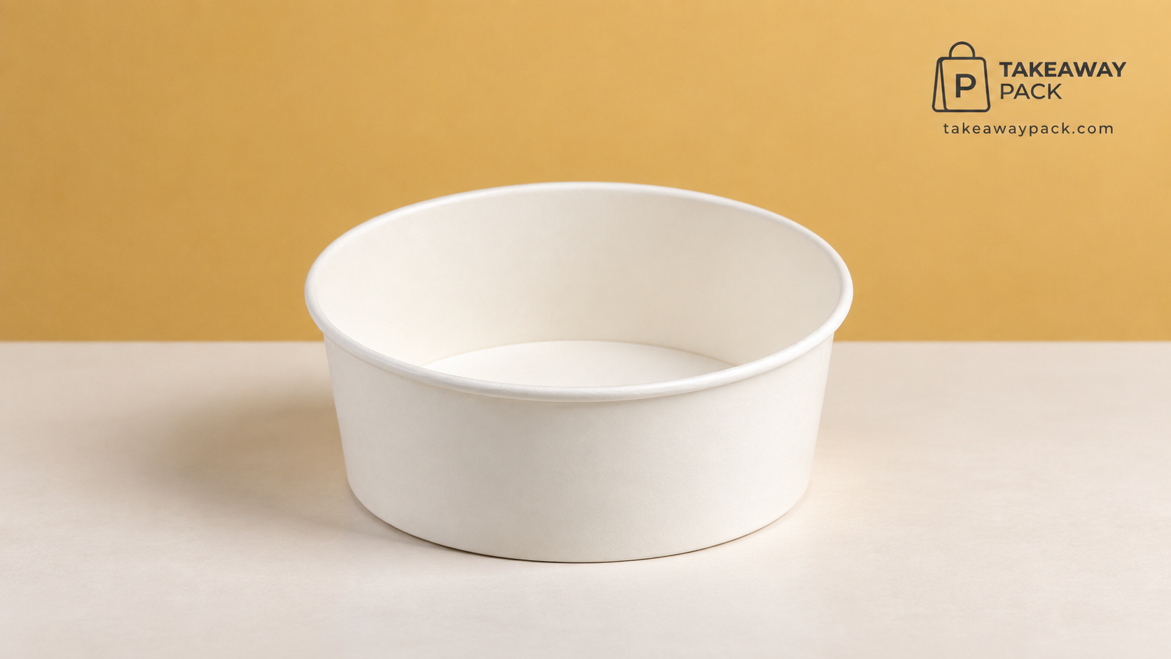 Empty round white paper takeaway bucket standing on a pale surface against a mustard-yellow background.