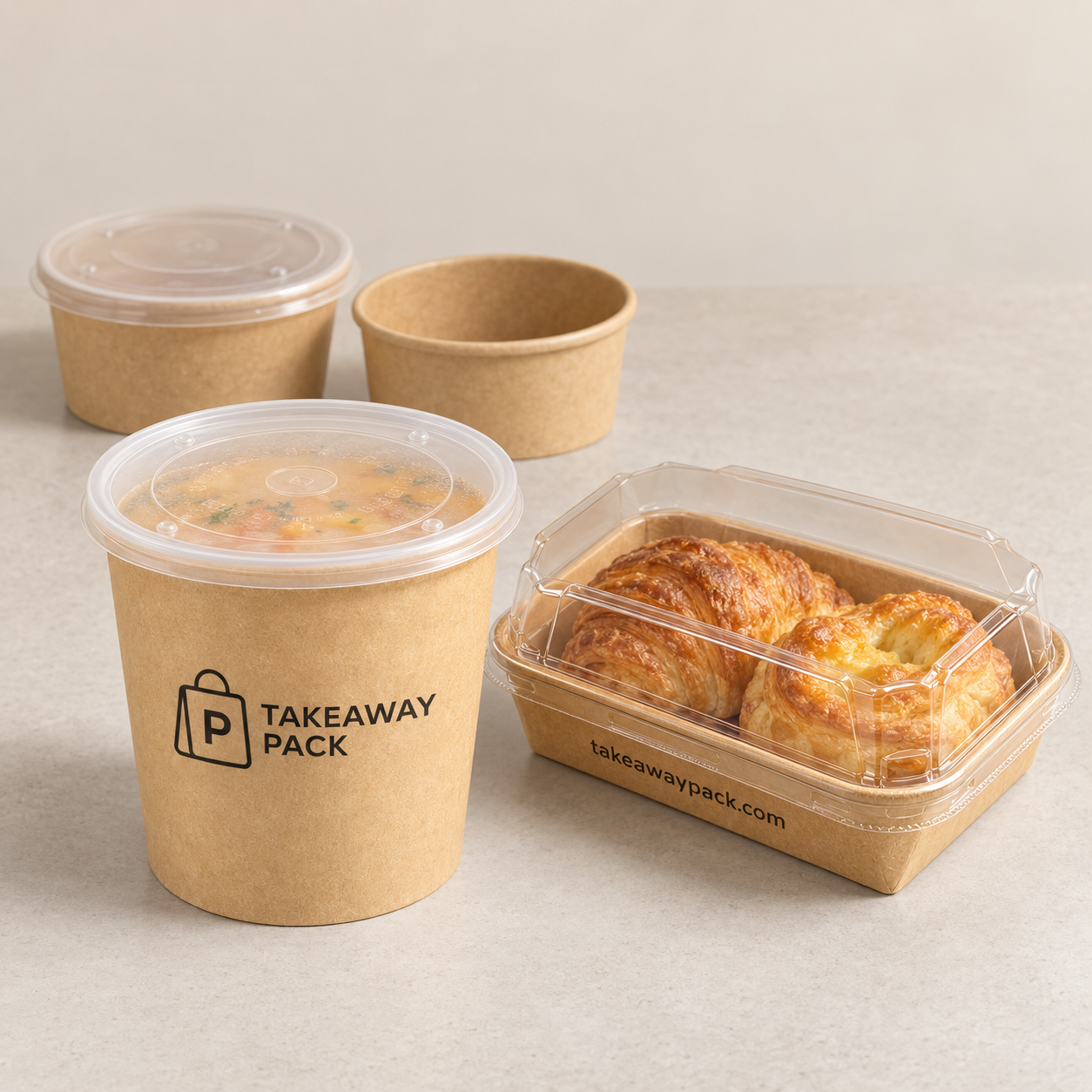 Three brown paper cups, two fitted with clear plastic lids and one holding a brown drink topped with green garnish, next to a clear plastic box containing two golden baguettes.