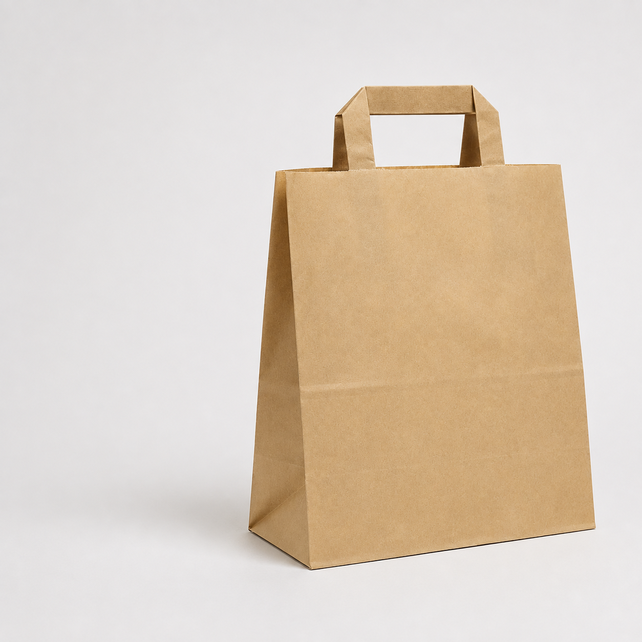 Plain kraft paper takeaway bag with flat handles on a light background