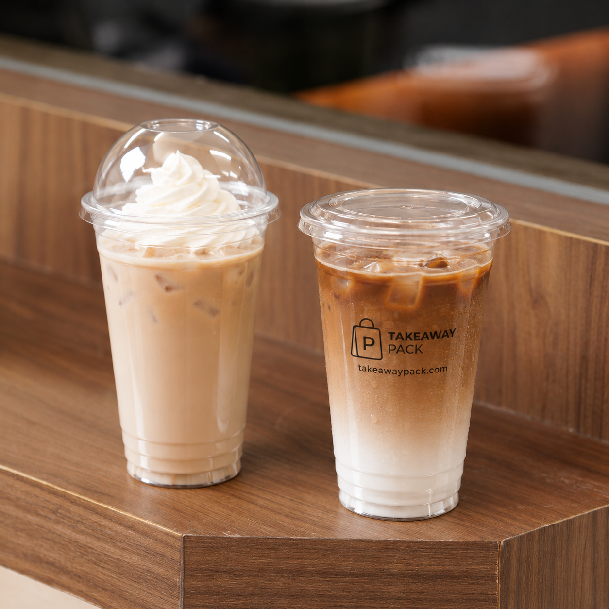 Clear PET cold cups with lids on a dark walnut café counter