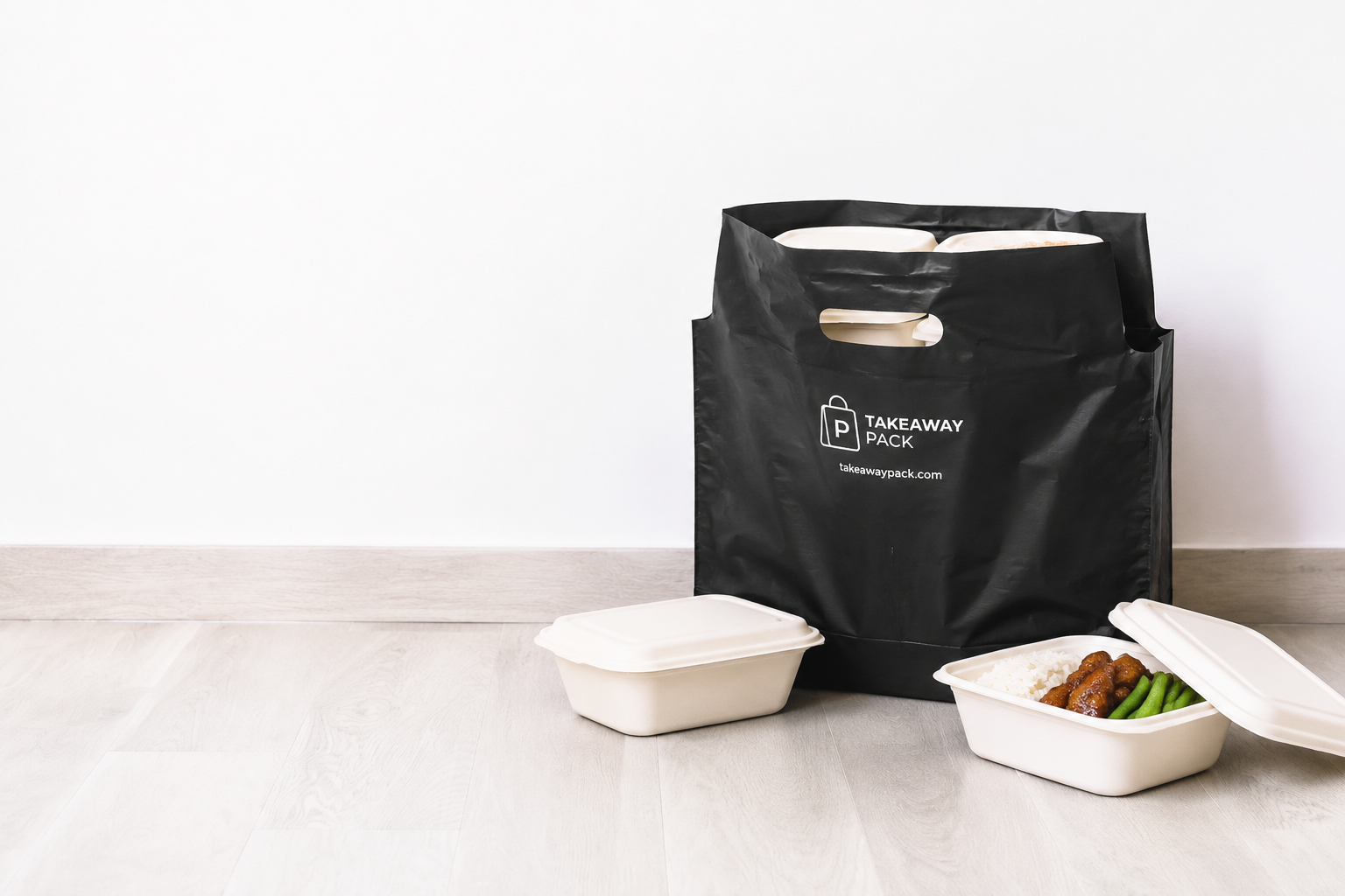 Black takeaway carrier bag with bagasse meal containers on a wooden floor